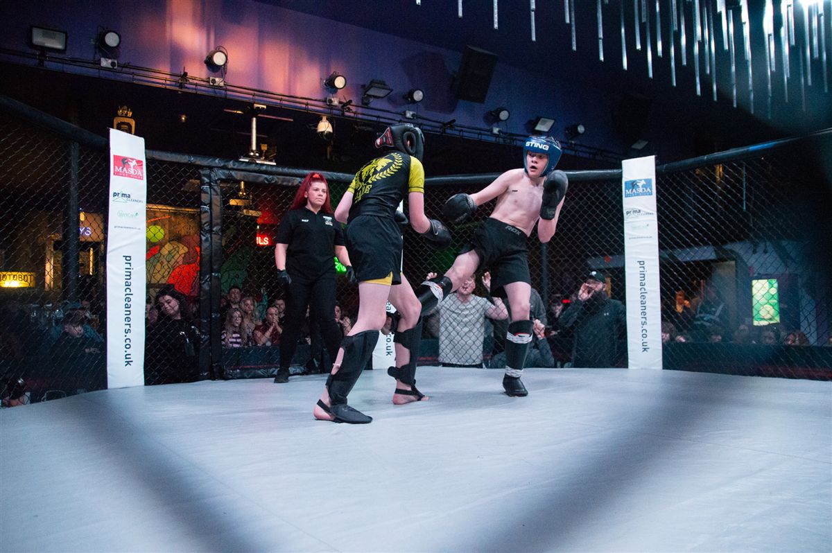 Two amateur fighters in full protective gear competing in the cage