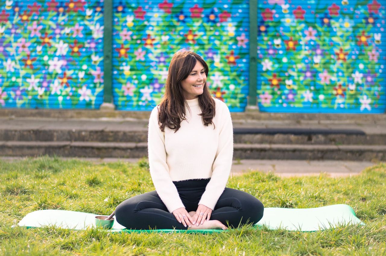 Nic, yoga and meditation teacher, sitting cross-legged on a mat